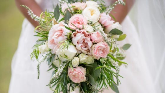 A bride holding a light pink wedding bouquet
